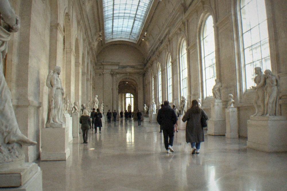 A skylighted sculpture gallery in the Louvre with marble statues along both walls