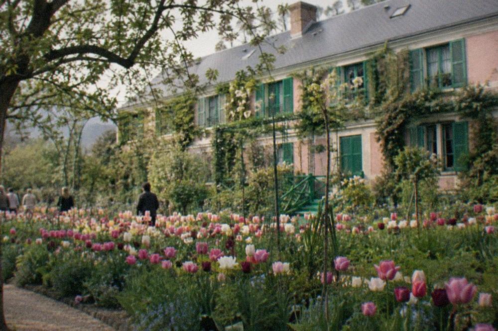 The flower garden at Giverny with rows of tulips and the pink farmhouse behind