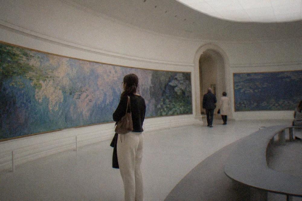 Oval gallery with curved walls holding wide water lily panoramas under soft skylight