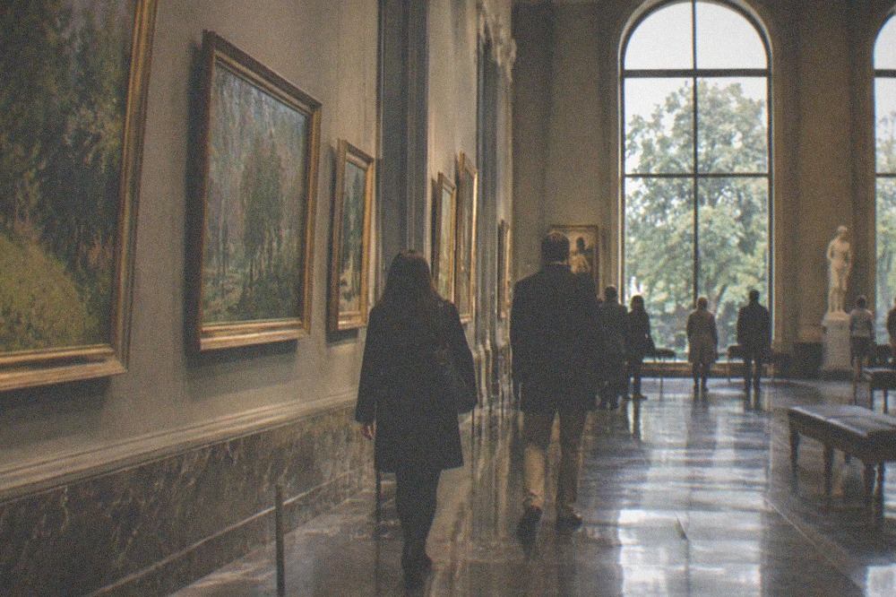 Impressionist gallery hall with tall arched windows and paintings hung in rows