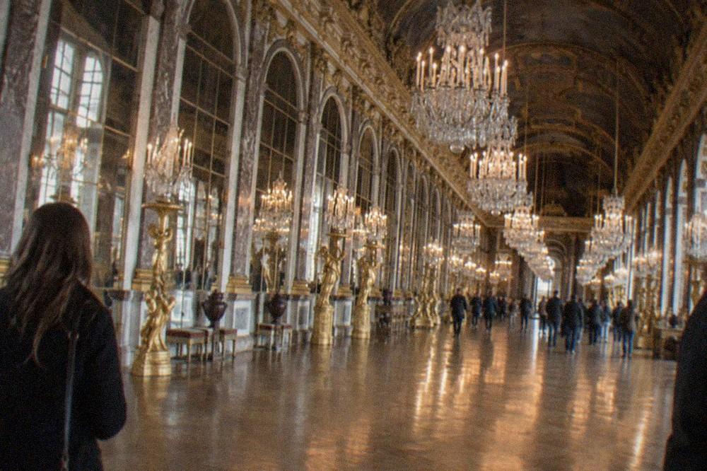 The Hall of Mirrors with chandeliers and gilded arches reflecting in the polished floor