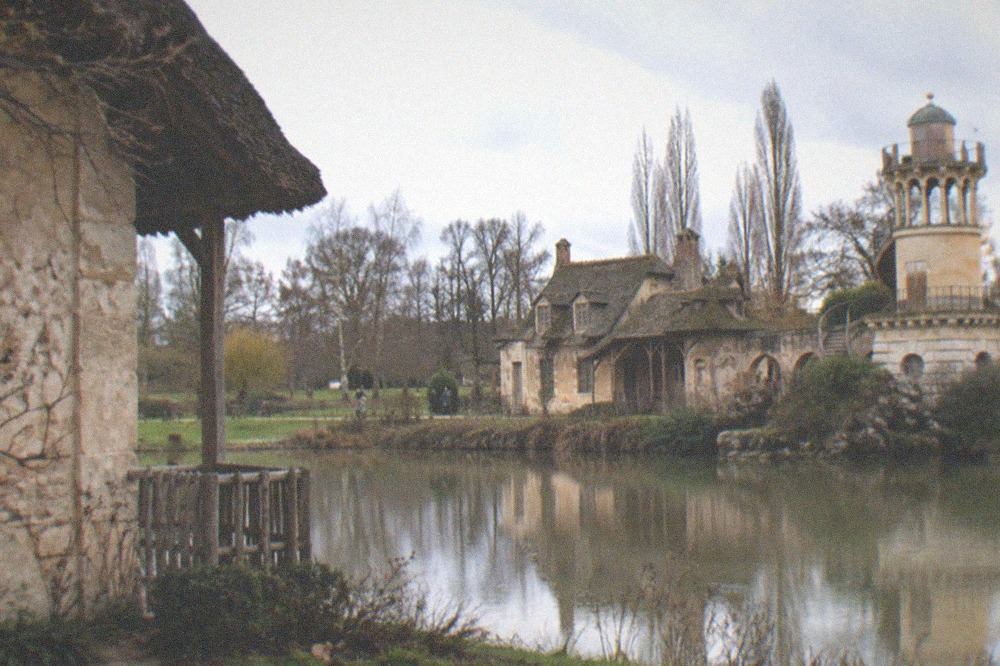 The Queen's Hamlet with a thatched cottage and a small lake reflecting the trees