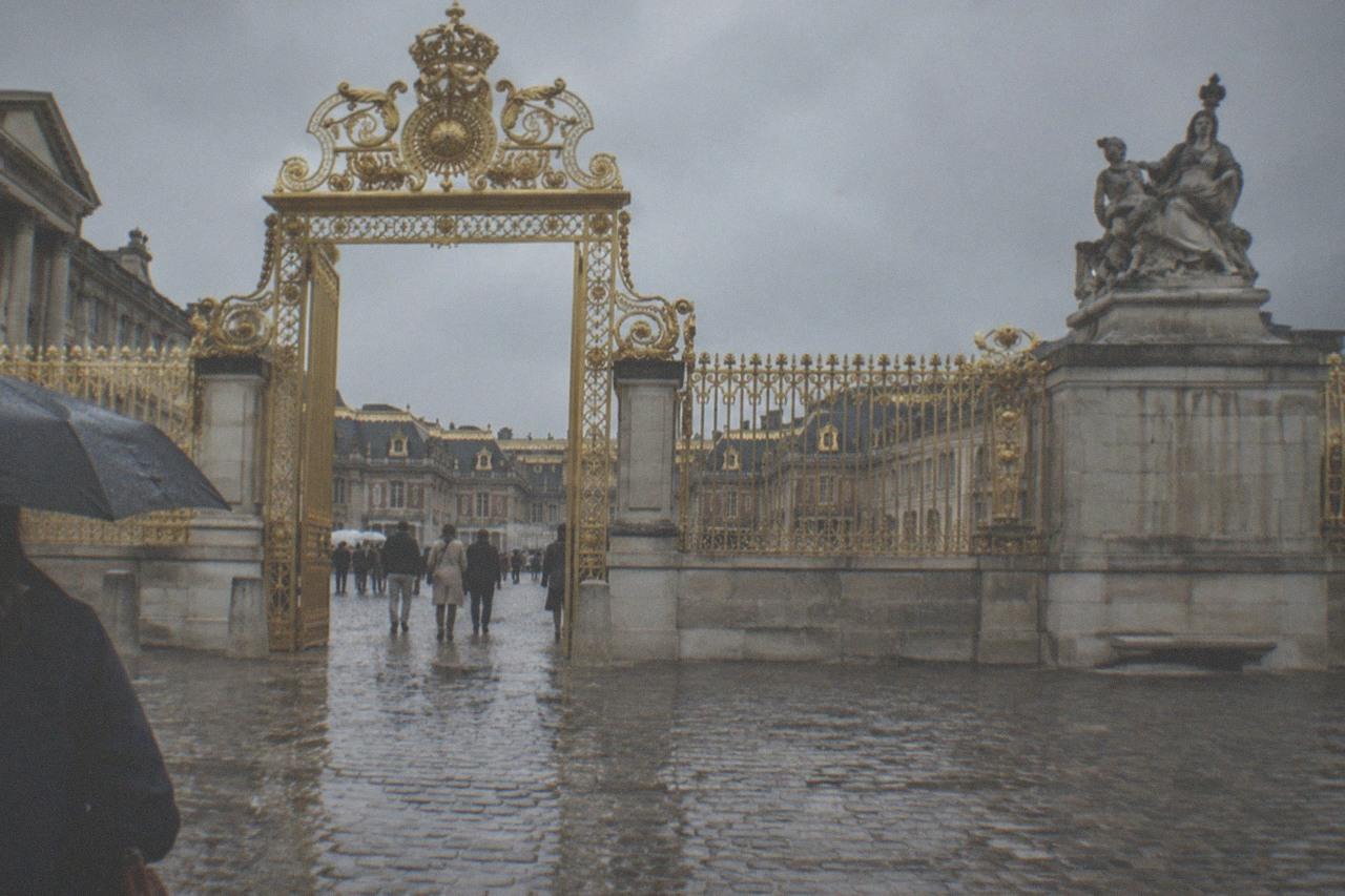 The gilded gates of the Palace of Versailles with the cobbled courtyard beyond