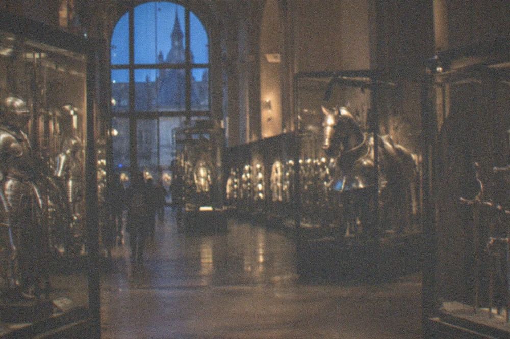 A gallery of polished medieval armour and swords displayed in glass cases inside the Musée de l'Armée