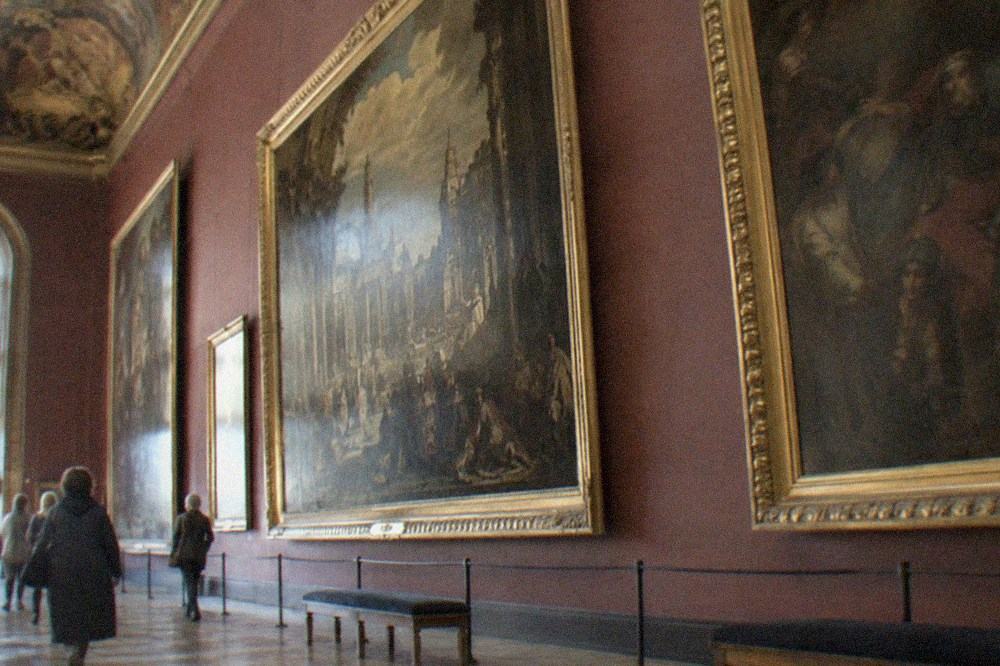 Gallery walls hung with large framed oil paintings under a painted ceiling