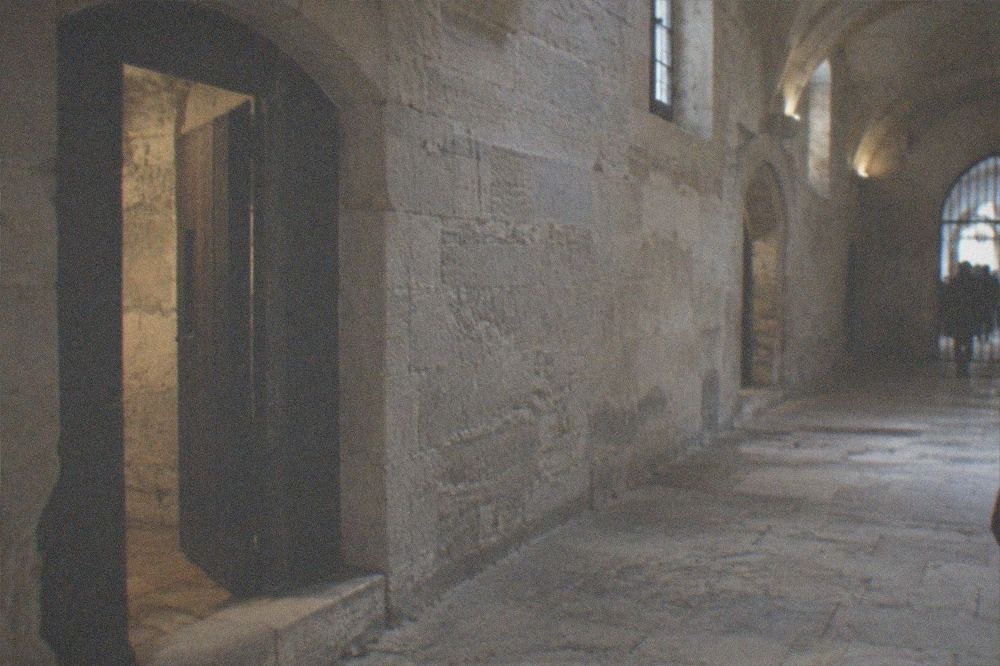Interior passageway of the Conciergerie with stone walls and arched doorways leading to the prison rooms