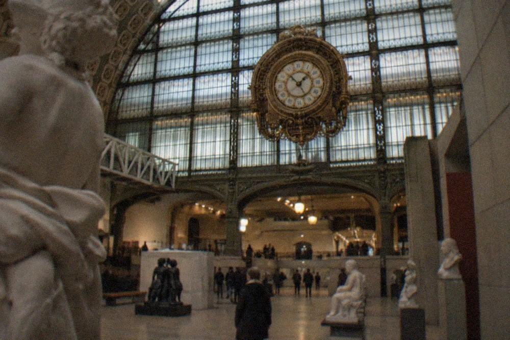 The interior of the Musée d'Orsay with the giant gilded clock glowing behind the gallery floor