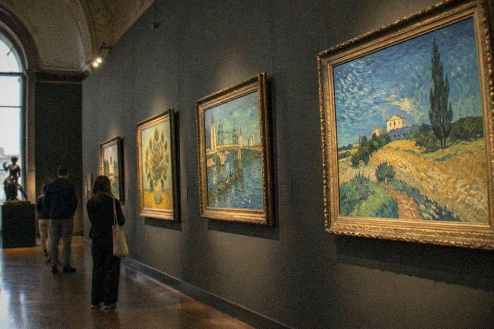 A gallery wall of Van Gogh paintings under spotlights inside the Musée d'Orsay