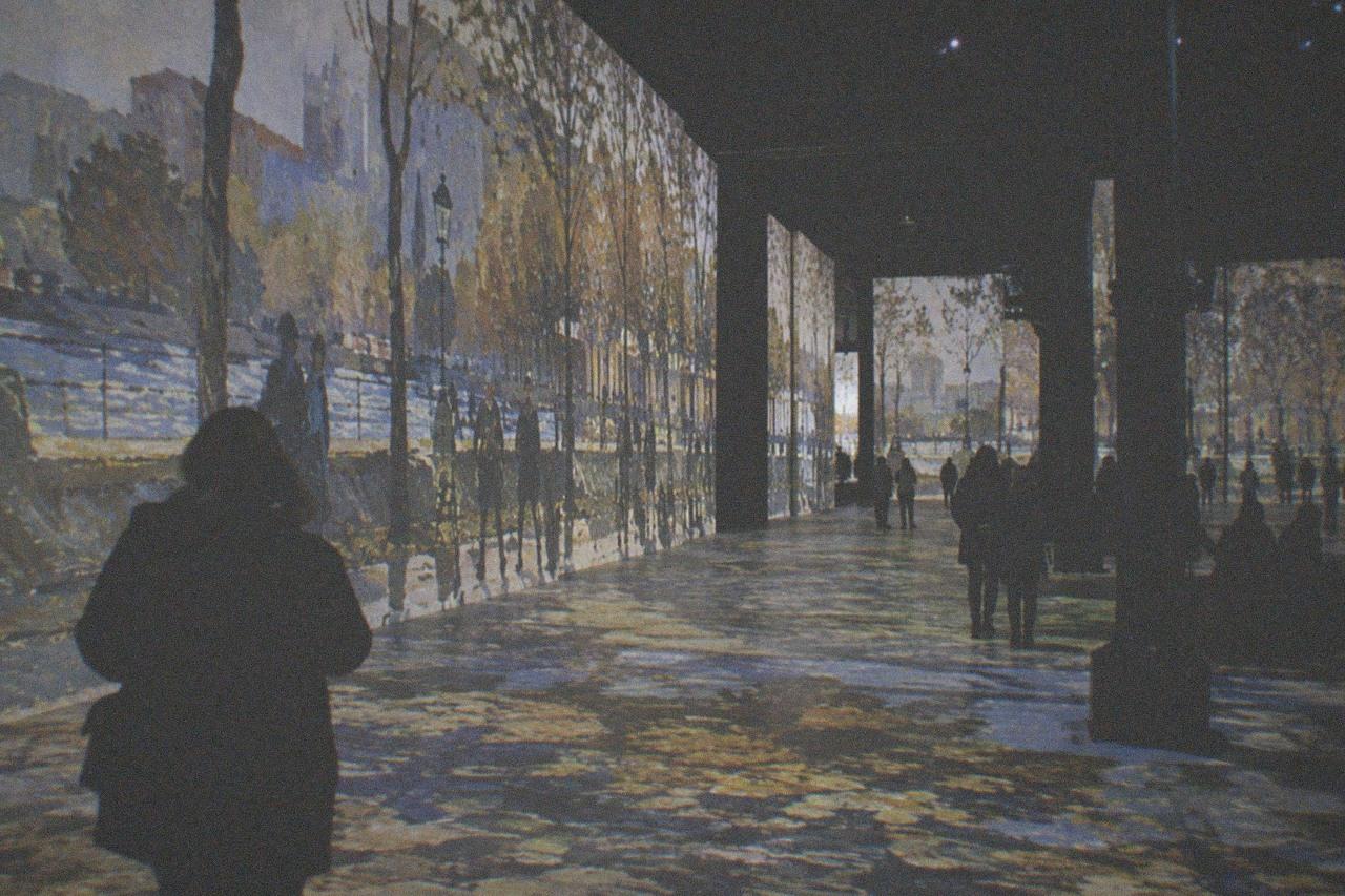 Projected artwork covering the walls and floor of a dark former foundry hall in Paris