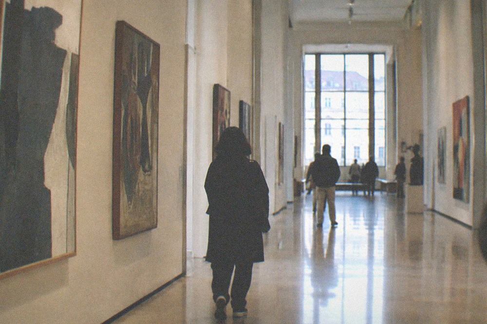 A museum gallery hall with modern paintings hung along both walls