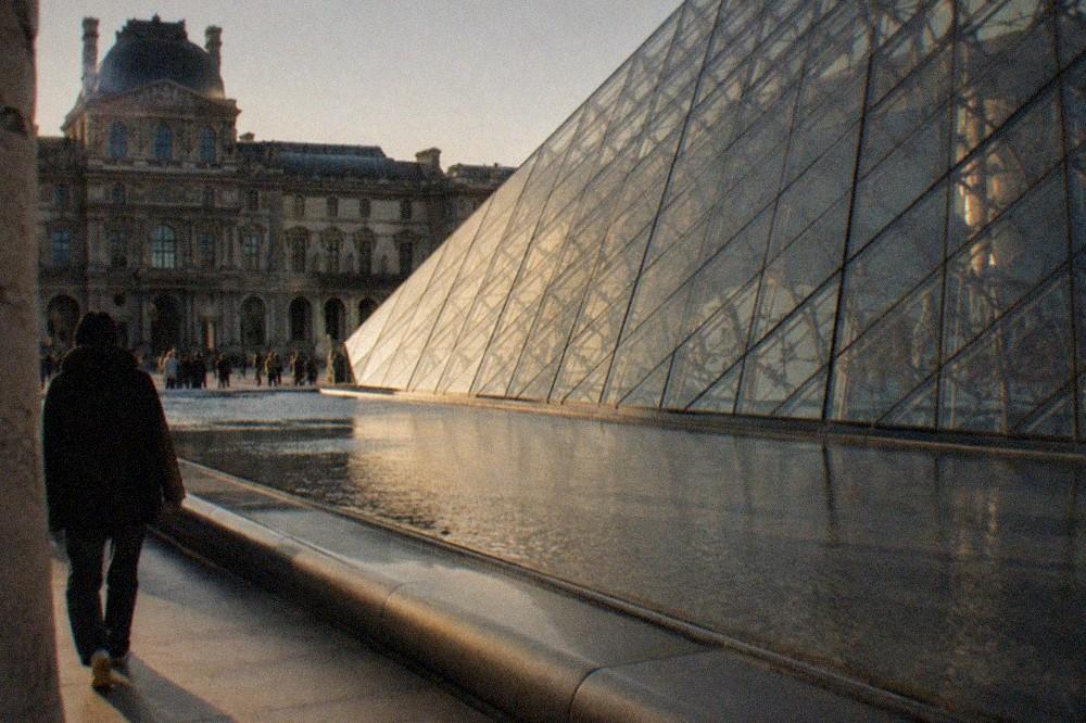 Overlapping glass panels of a contemporary museum facade seen across still water