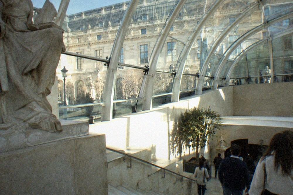 Curved white steel ribs supporting glass panels above a museum stairwell