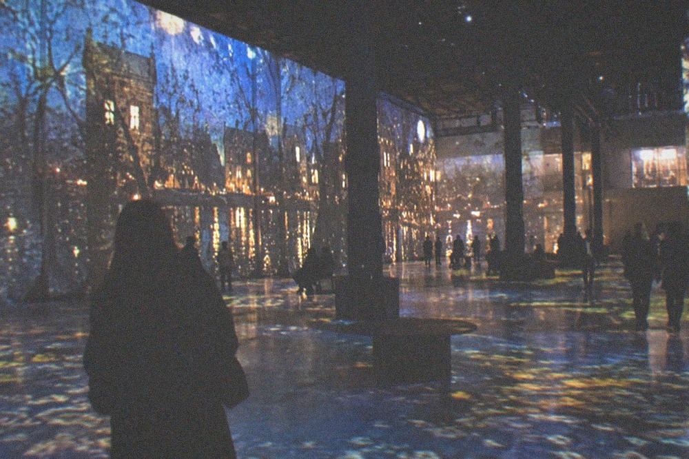 Projected light patterns covering the walls and floor of a dark industrial hall