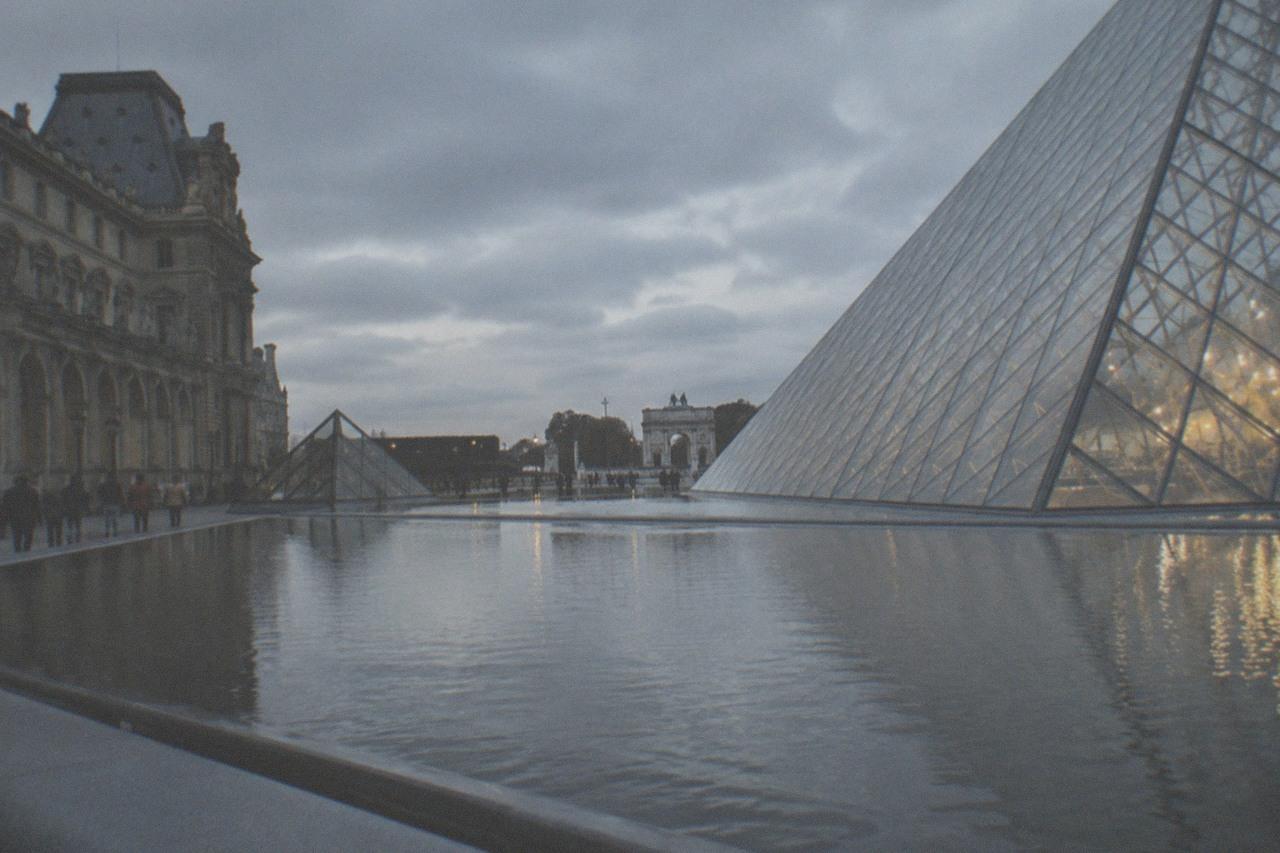 Glass sail structure of a modern art museum reflected in water at dusk