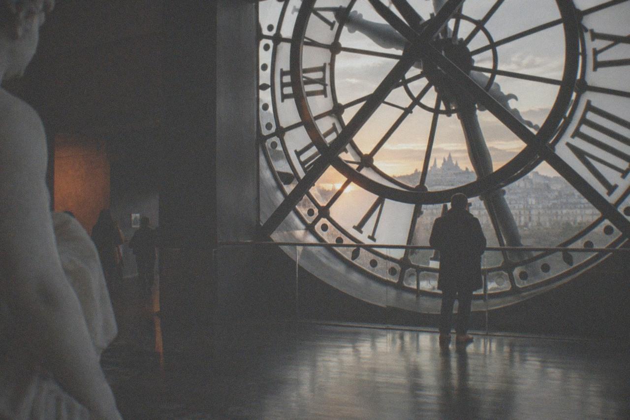 The grand clock window of a converted railway station overlooking the Seine at golden hour
