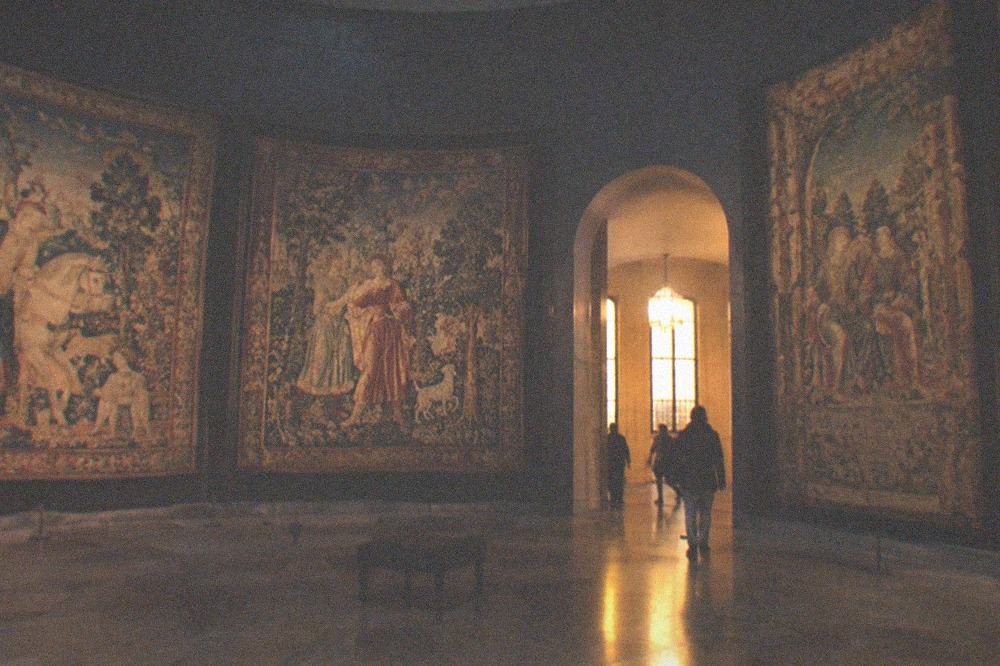 Medieval woven hangings displayed in a dim circular gallery room