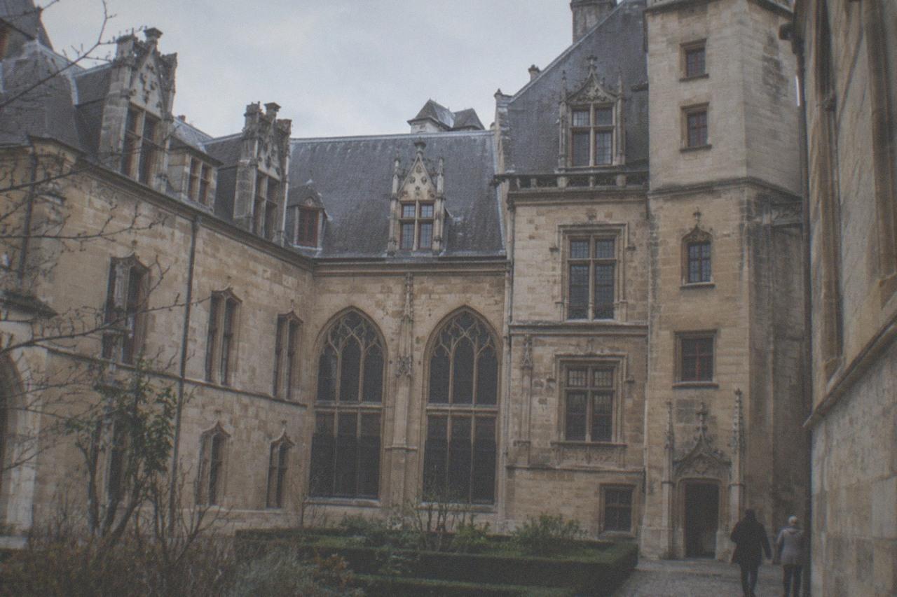 The stone facade and arched windows of the Hotel de Cluny museum in Paris