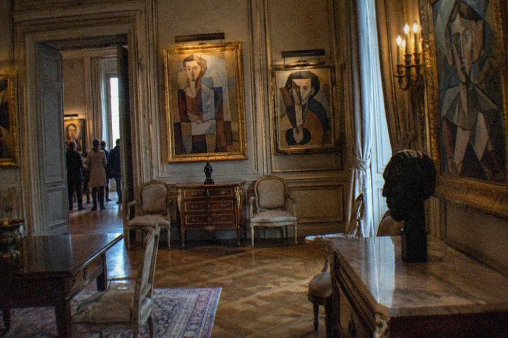 Gallery wall of framed Picasso paintings in a mansion room with parquet floor