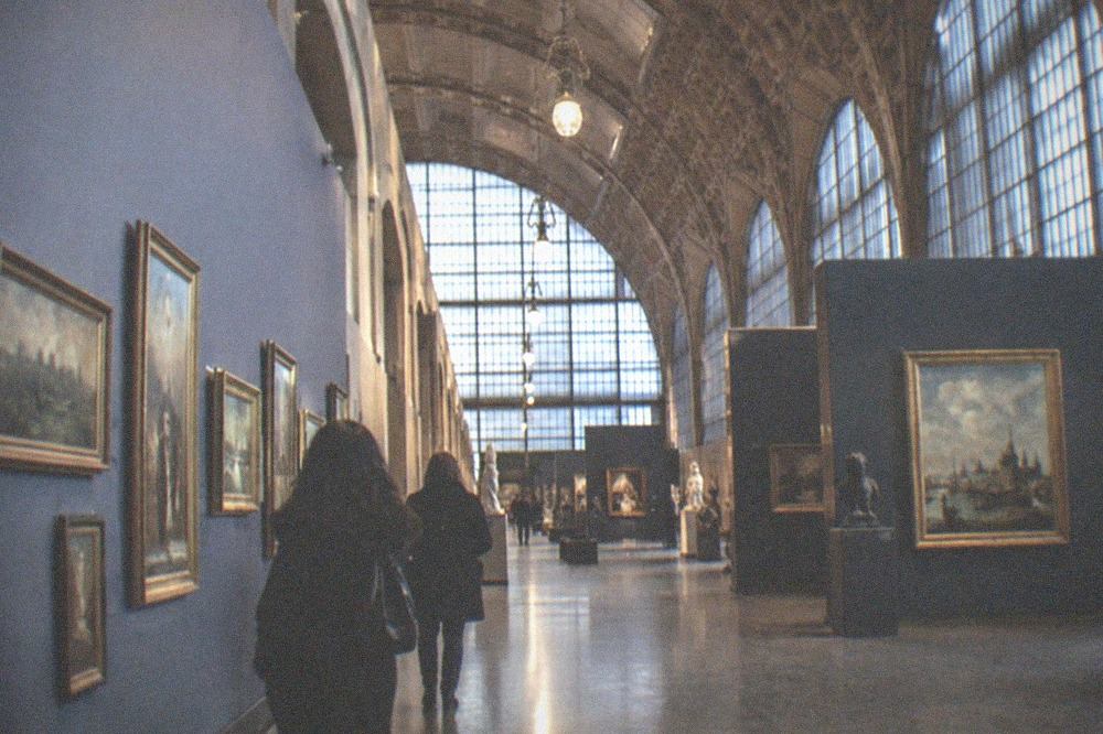 Rows of paintings in a sunlit gallery of a converted railway station museum