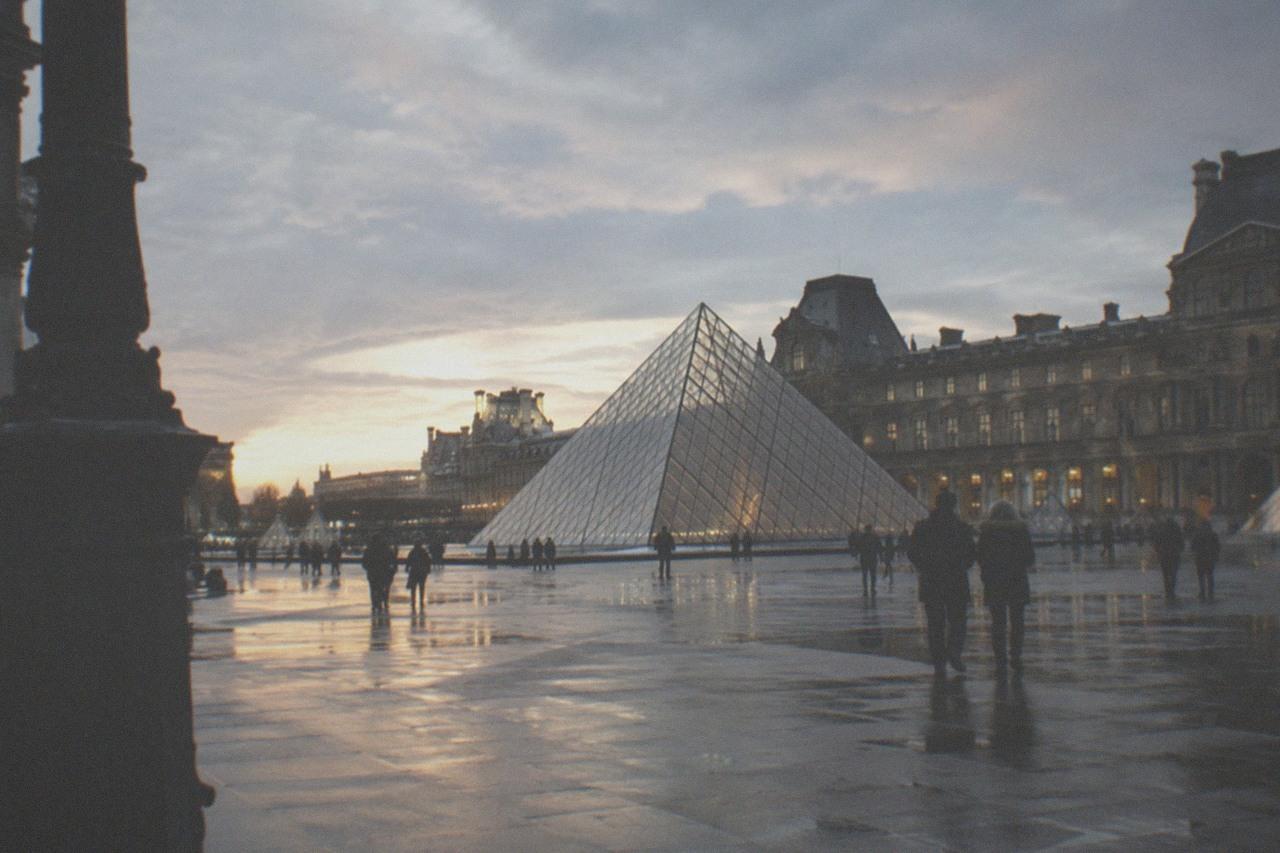 The Louvre glass pyramid glowing above the palace courtyard at dusk