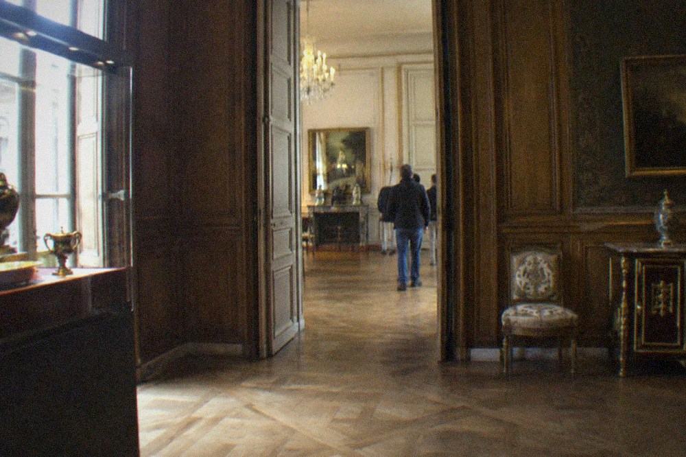 A museum gallery of historic Paris interiors with wood panelling, display cases and soft lighting