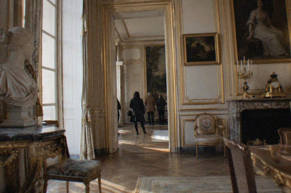 A formal interior of a Paris mansion museum with gilded panelling, marble sculpture and oil paintings hung above a fireplace