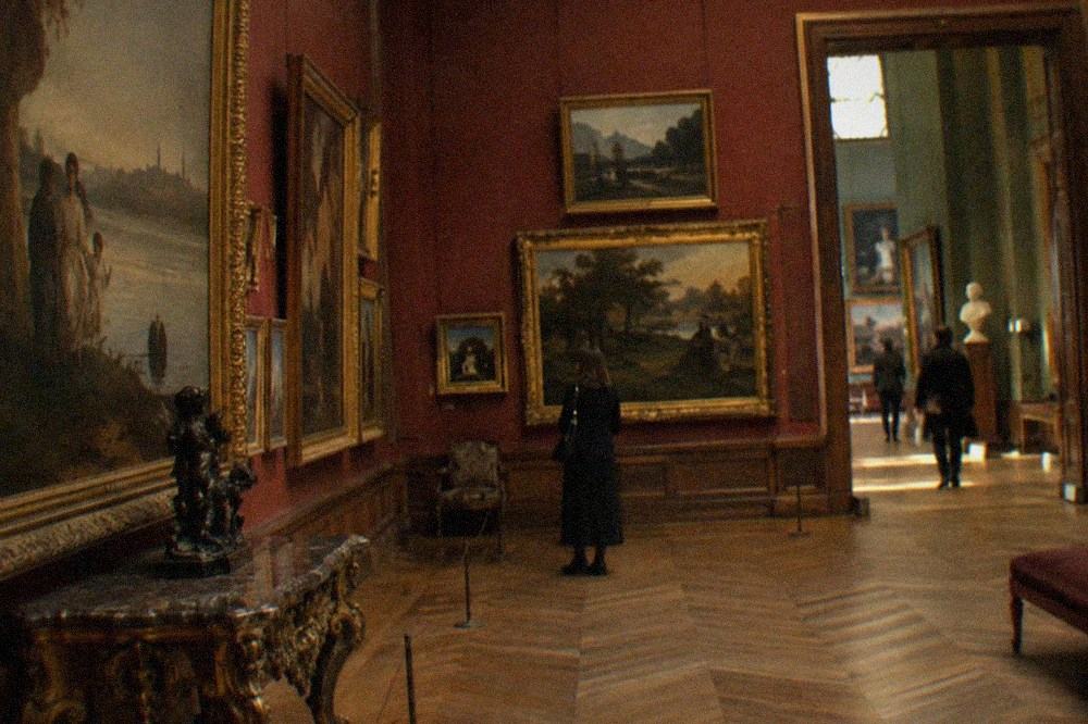 A gallery of nineteenth-century French paintings hung on deep red walls in the Petit Palais