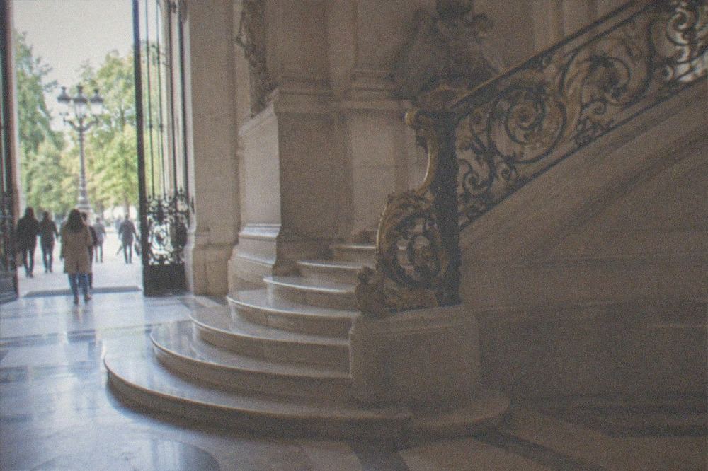 A wide stone staircase and gilded ironwork railing inside the entrance hall of the Petit Palais