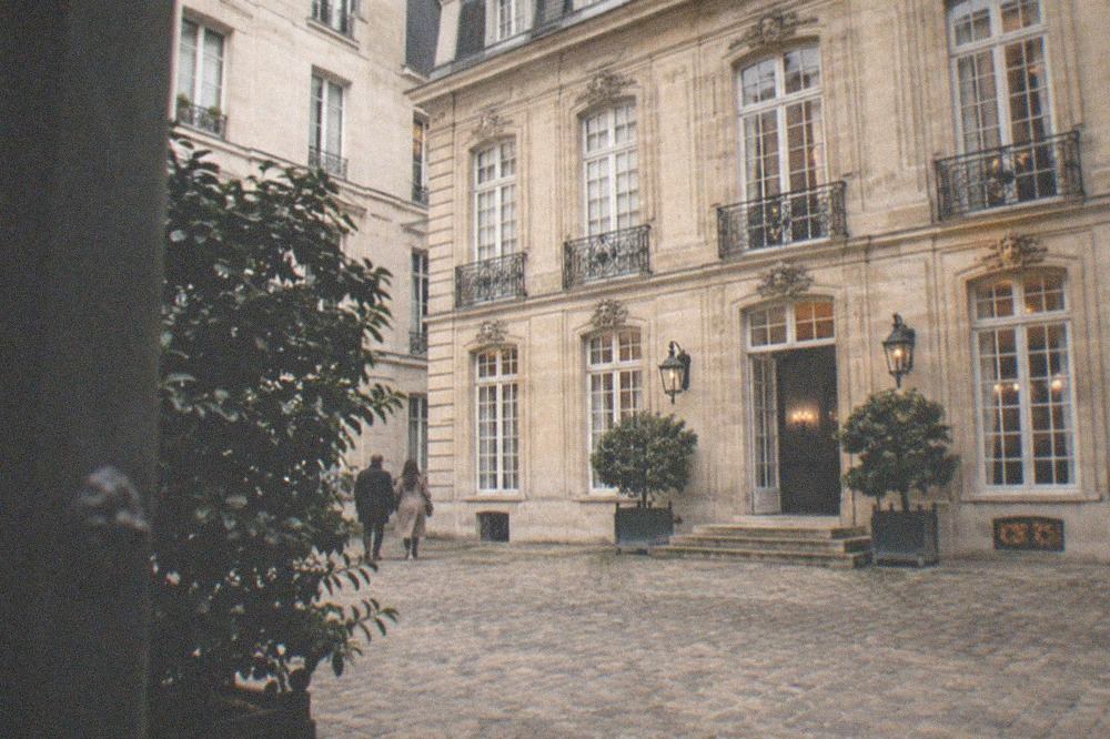 A townhouse facade with tall windows above a cobbled courtyard