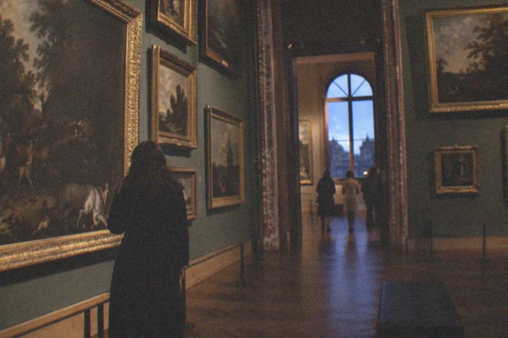 Rows of paintings filling the walls of a classical picture gallery