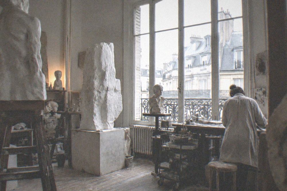 A sculptor's studio with large plaster figures, a high window and work benches.