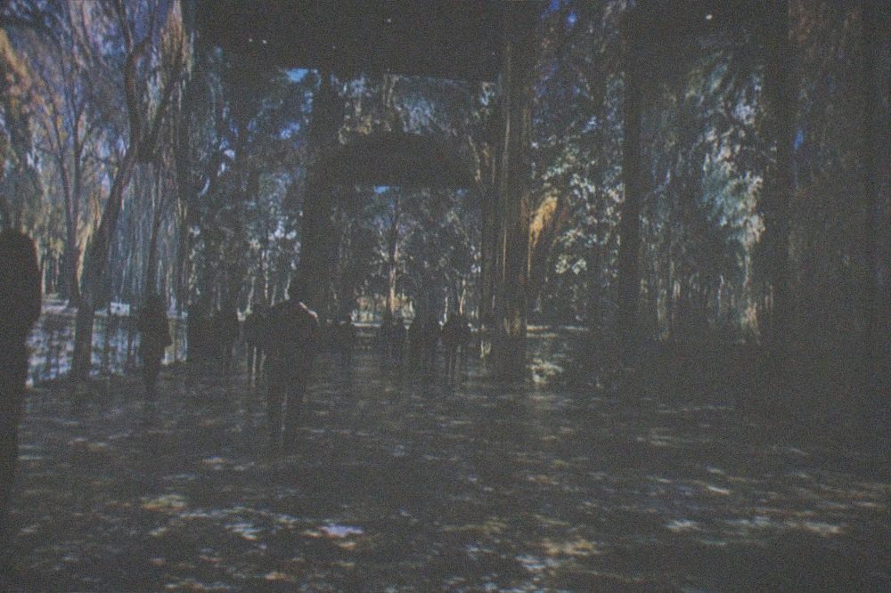 A vast dark hall with moving projected light covering the walls and floor.