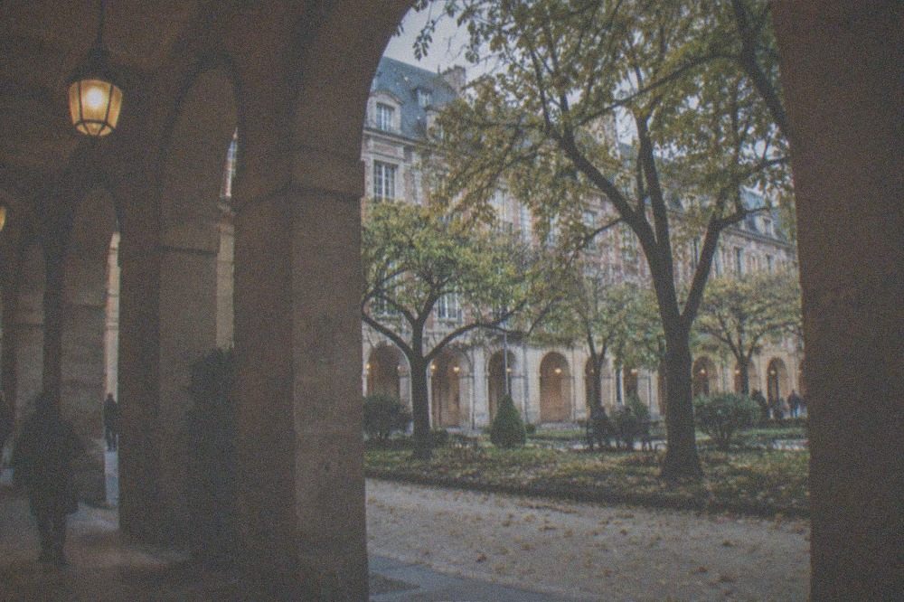 Leafy square surrounded by stone arcades in the Paris Marais