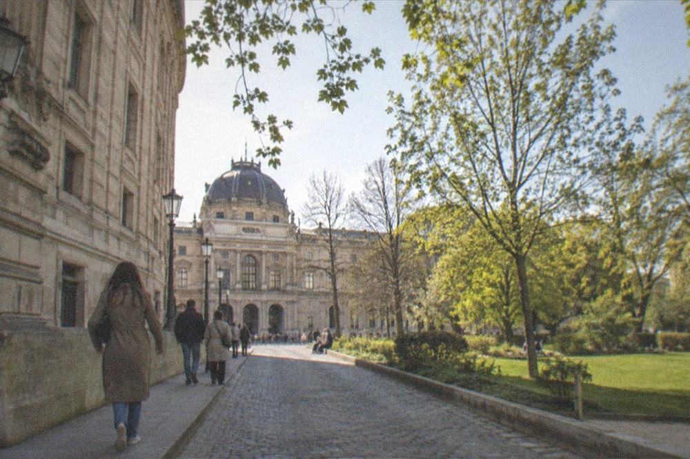 Cobbled Paris street with historic buildings leading toward a museum entrance