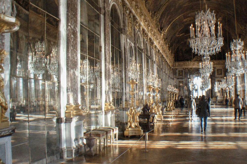 The Hall of Mirrors at Versailles with light reflecting along the gallery of arches