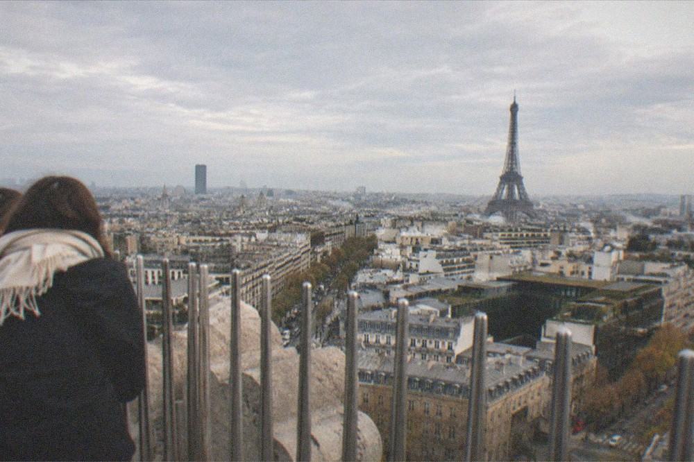 A panoramic view over Paris rooftops from the Arc de Triomphe terrace with the Eiffel Tower in the distance