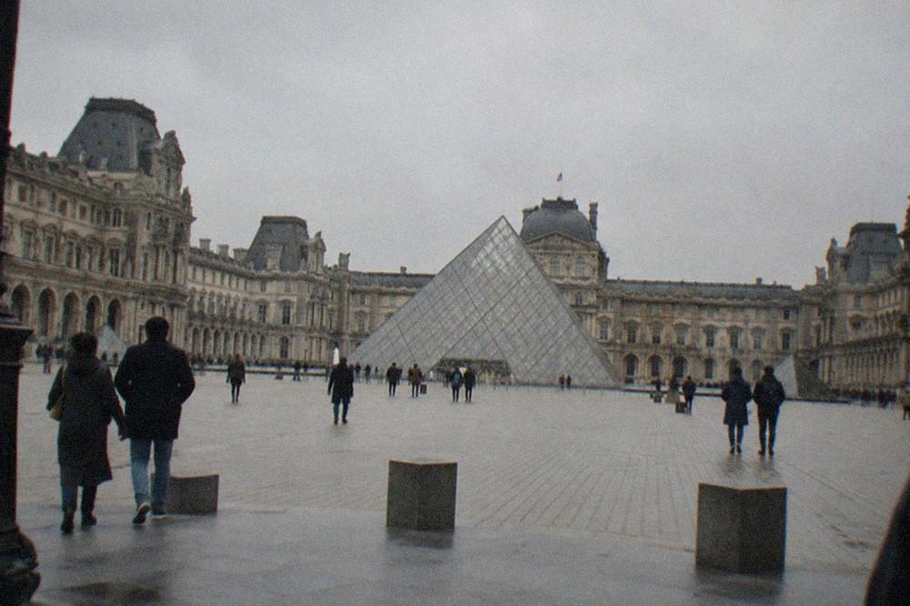 The Louvre palace courtyard seen from outside with the glass pyramid ahead