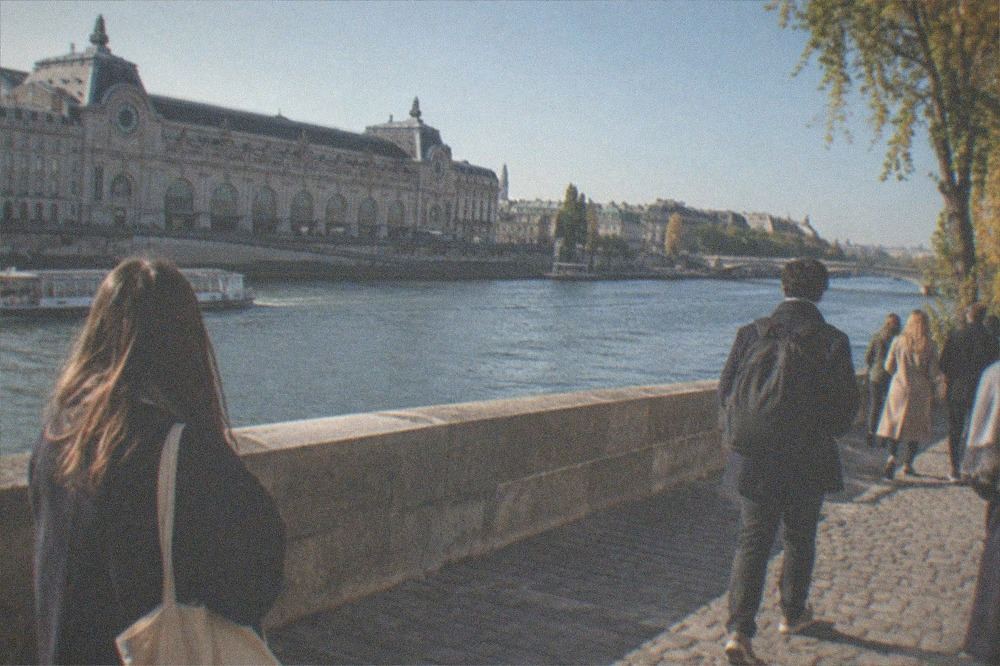 Visitors walking along the Seine riverbank with the Orsay building across the water