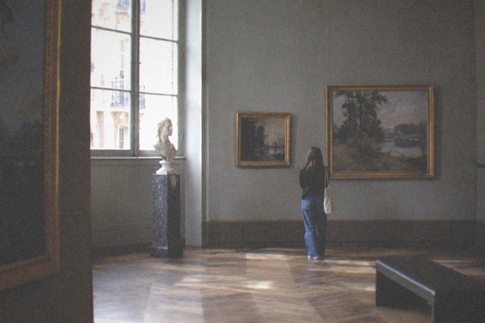 A quiet gallery room with paintings hung on deep walls