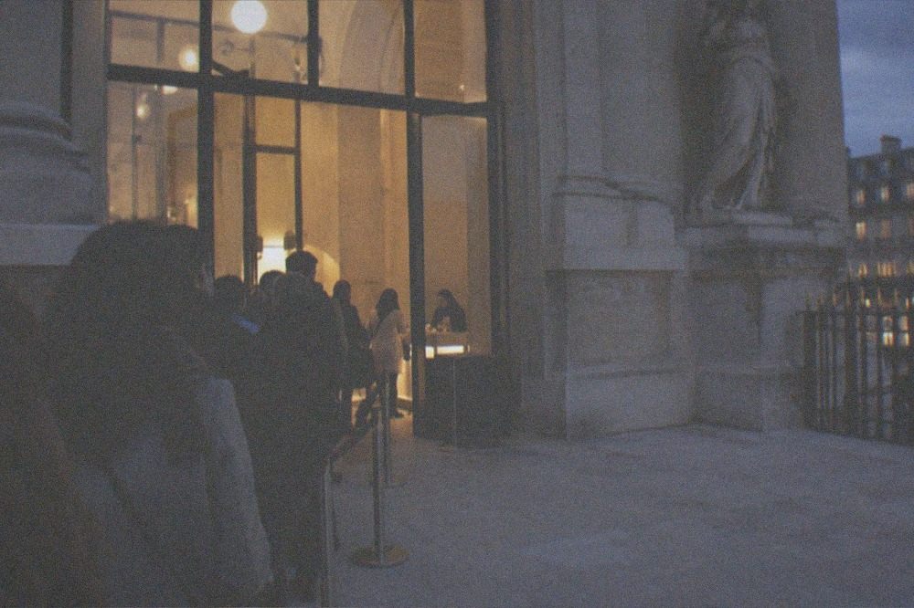 A museum ticket desk with a small queue of visitors waiting