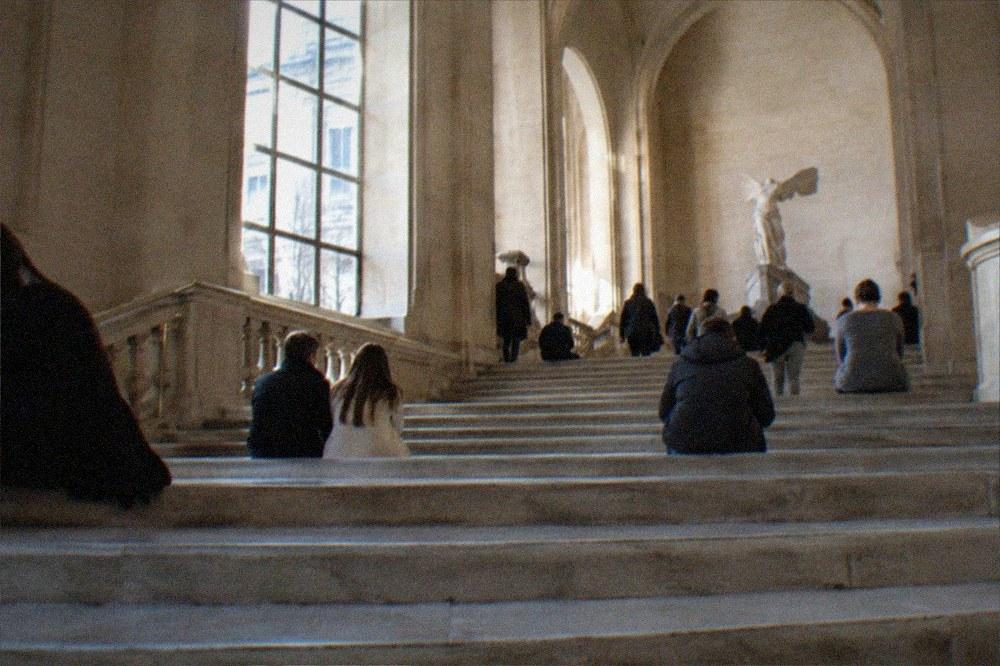 A wide stone staircase inside a museum with visitors resting on the steps
