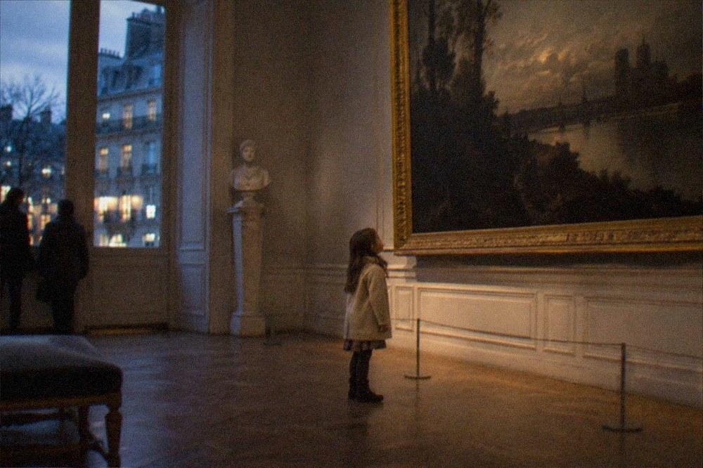 A child looking up at a large framed painting in a quiet corner gallery