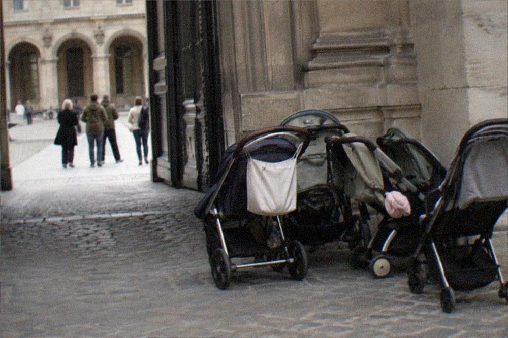 A family of strollers parked outside a museum entrance in a Paris courtyard