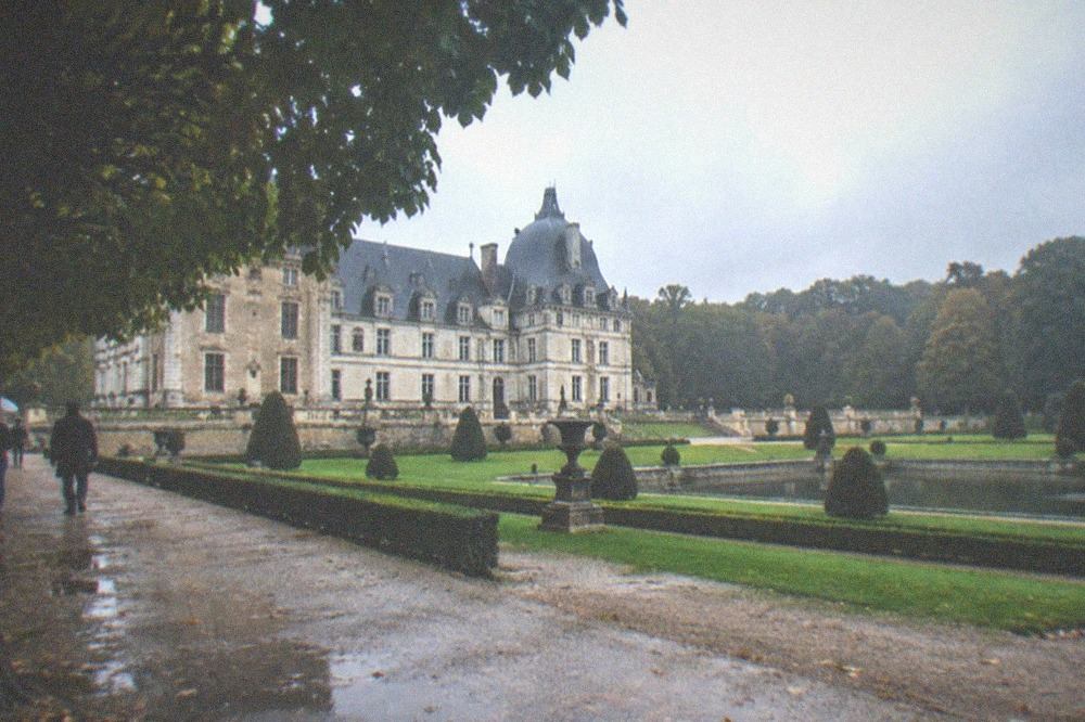 Renaissance chateau beside formal gardens with water features and tree-lined paths