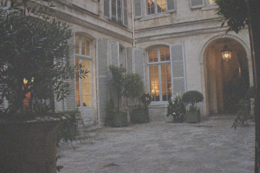 Quiet historic house museum courtyard with shuttered windows and potted greenery