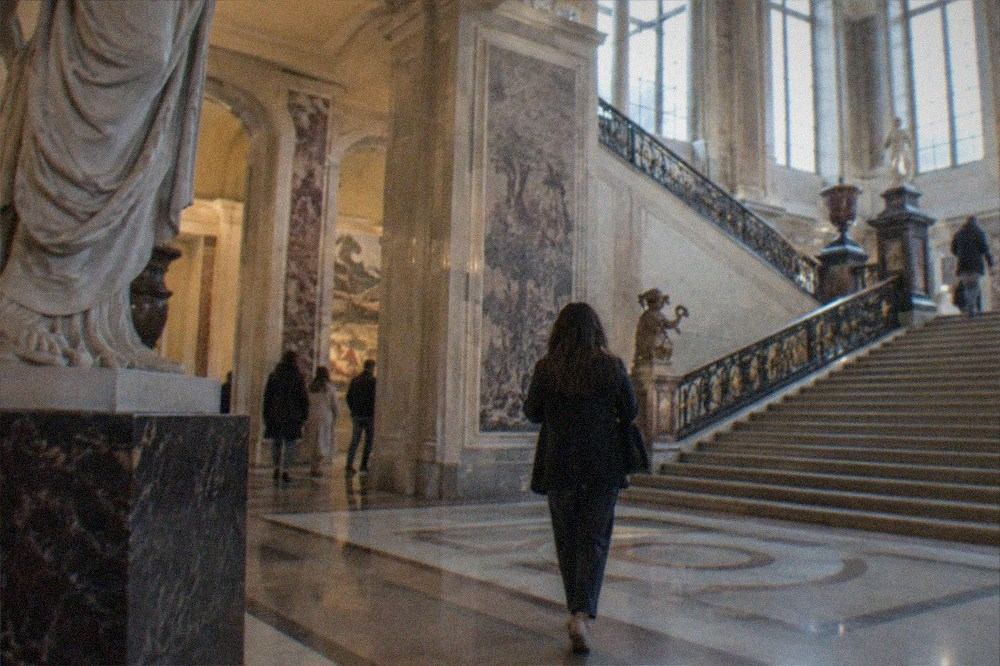 A grand marble house museum hall with a wide staircase and rain grey windows