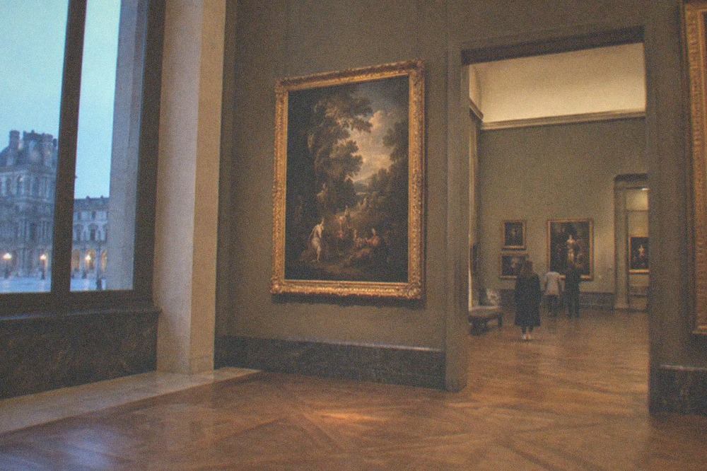 A quiet gallery inside the Louvre with a painting gallery and few visitors in the afternoon
