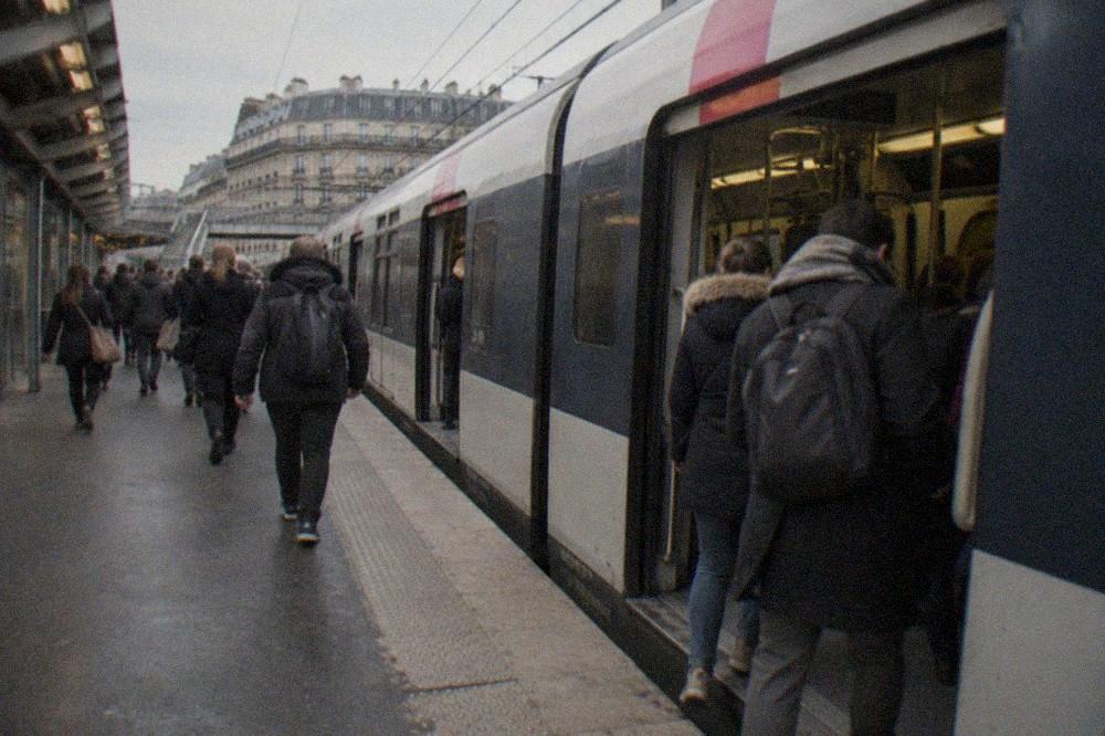 A suburban RER train at a Paris station platform with passengers boarding