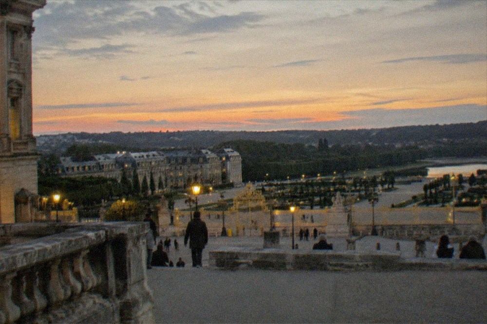 A wide view over the Versailles estate rooftops and gardens from the town approach at sunset