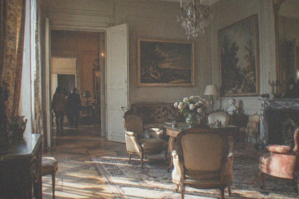 A salon in a former hunting lodge hung with Impressionist paintings under a chandelier